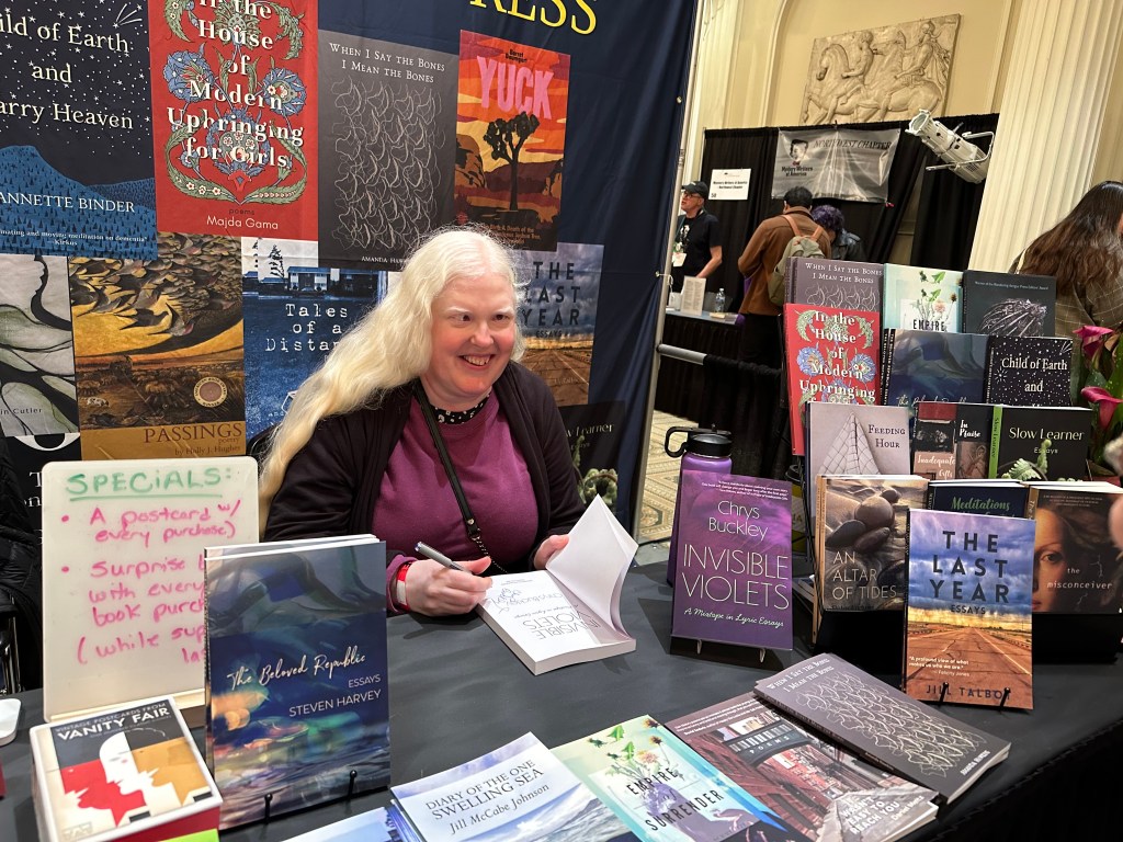 Chrys Buckley signing advanced reader copies of Invisible Violets at the Wandering Aengus Press booth at the Portland Book Fest