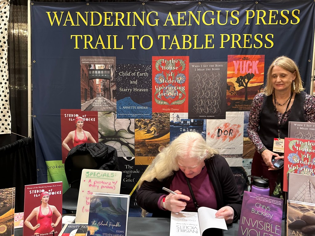 Chrys Buckley signing advanced reader copies of her book Invisible Violets at the Wandering Aengus Press booth at Portland book fest